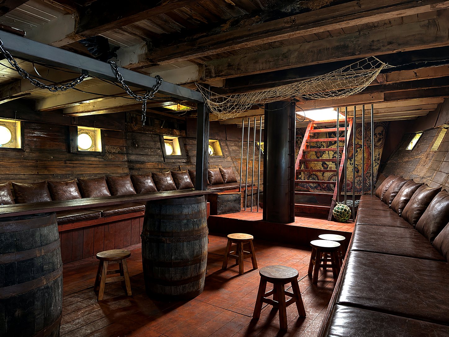 The Kraken's Hold looking toward the map-painted stairwell, with barrel tables and stools